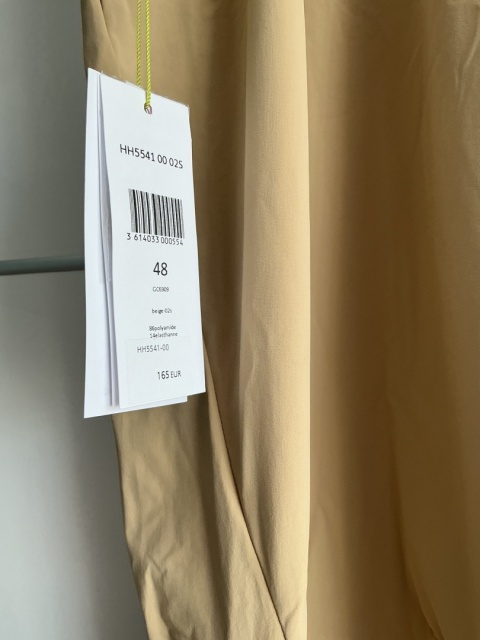 Zbliżenie na metkę spodni męskich Lacoste w kolorze beżowym.