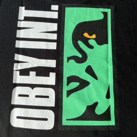 Zbliżenie na graficzny nadruk OBEY na czarnym T-shircie.
